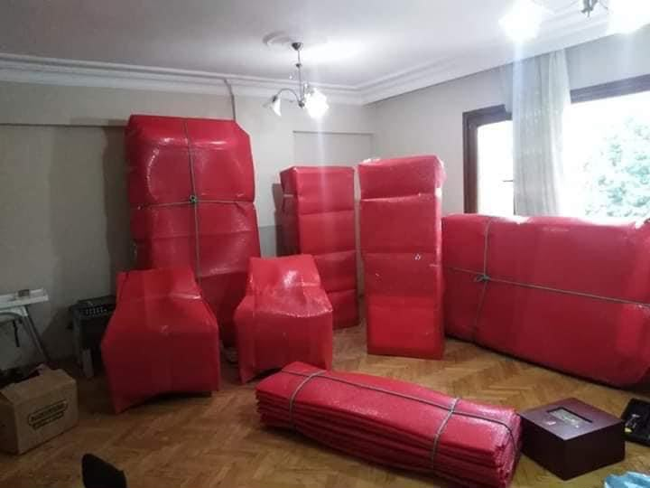 Kırmızı koruyucu örtülerle paketlenmiş salon mobilyaları